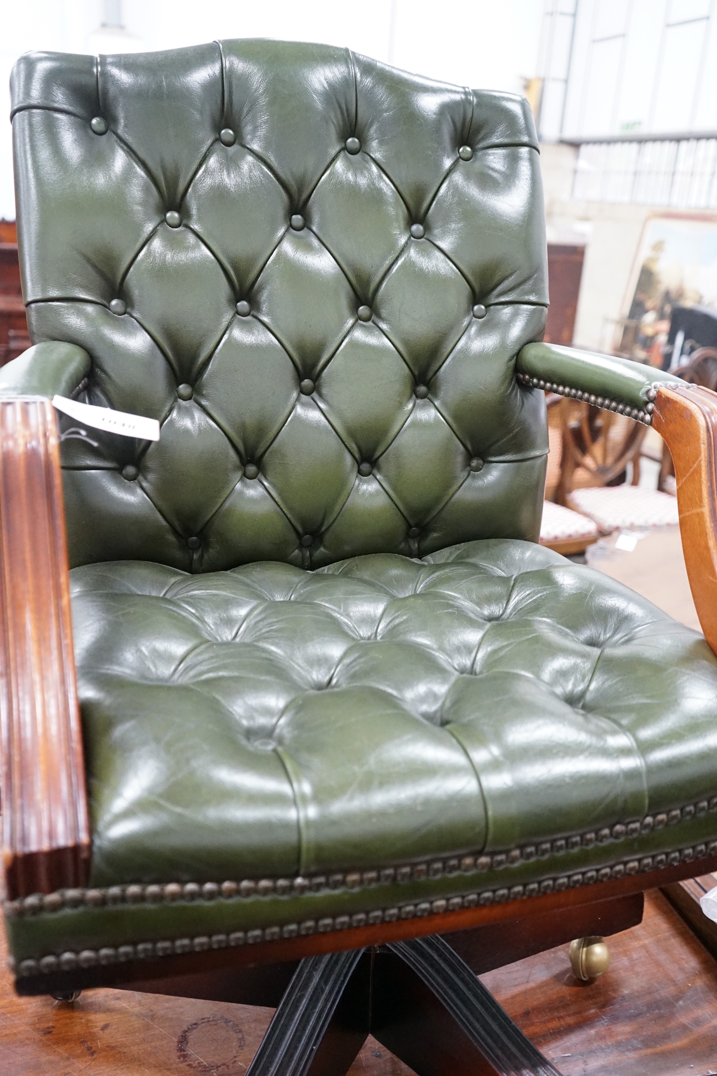 A reproduction mahogany and buttoned green leather swivel desk chair, width 56cm, depth 51cm, height 94cm